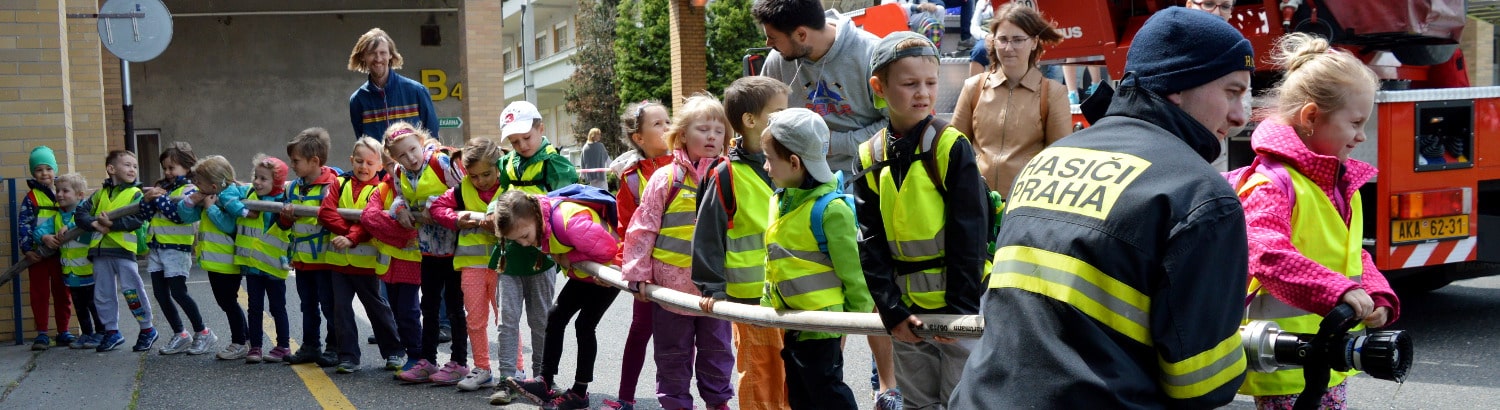 Děti v dlouhé řadě drží hasičskou hadici